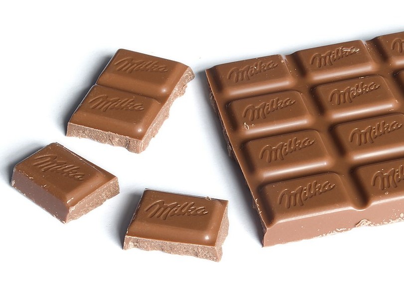 Milka chocolate bar (100g) with chunks broken off.