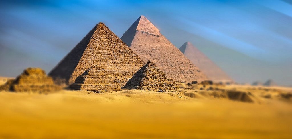 Photograph of the Pyramids of Giza in Egypt. Pyramid structure is often used metaphorically to explain modern financial scams like pyramid schemes.